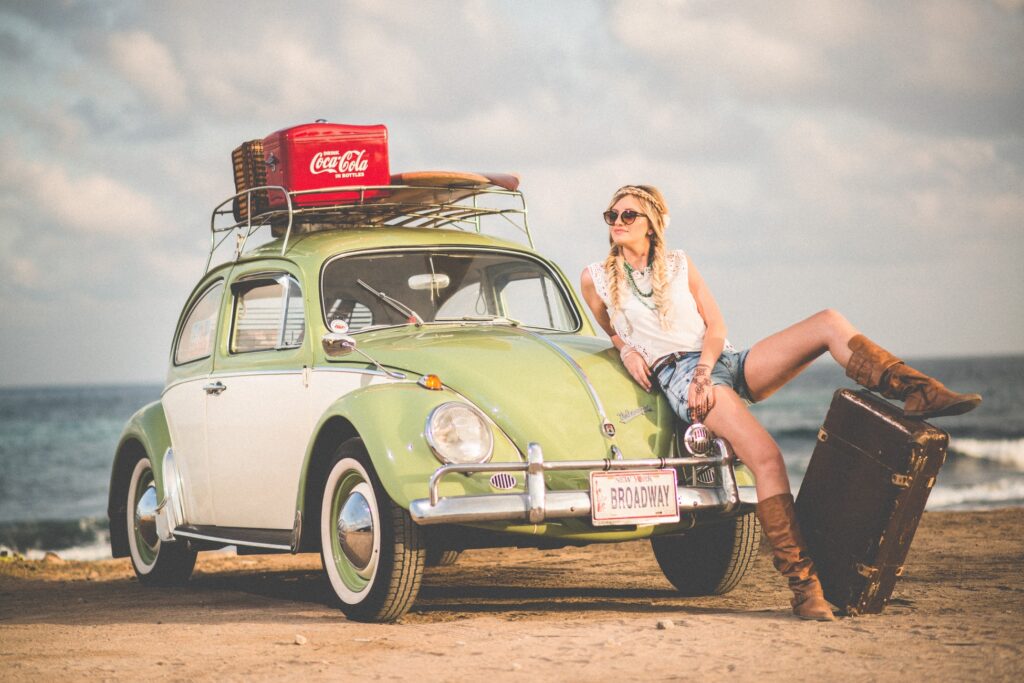 Woman by green vintage car in boots